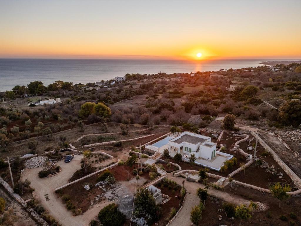 une vue aérienne sur une maison avec le coucher du soleil en arrière-plan dans l'établissement Villa Essenza, à Torre Vado