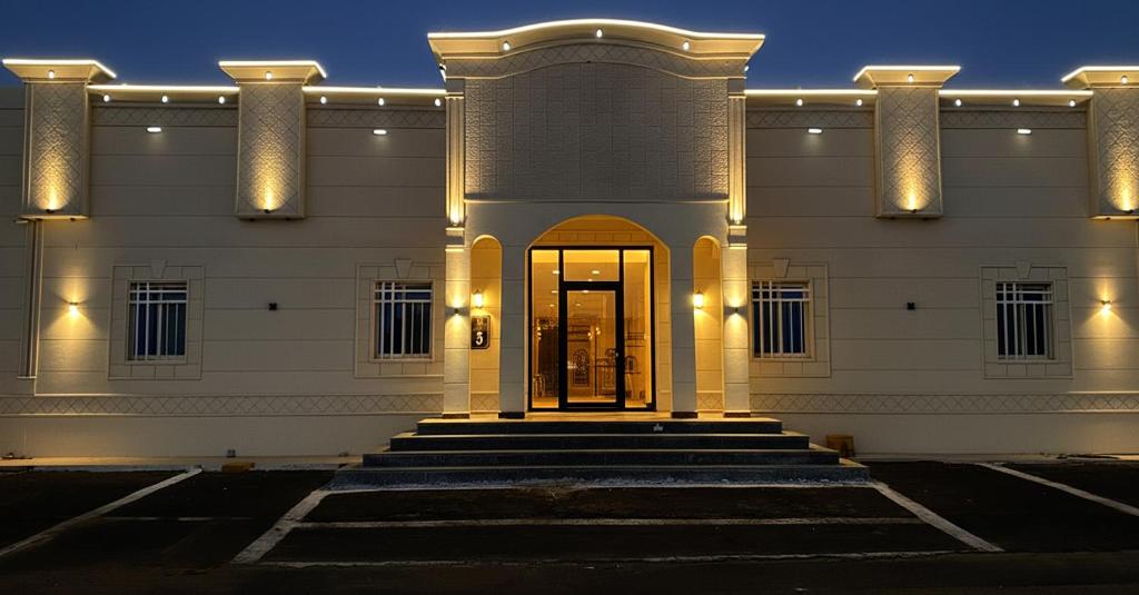 a large white building with a door and stairs at سما الراقية للشقق المخدومة in Najran