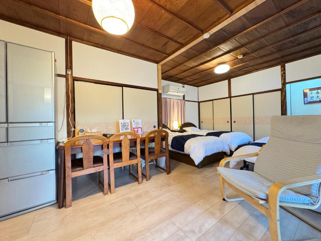 a bedroom with two beds and a couch and chairs at Jikka Japan in Izumi-Sano