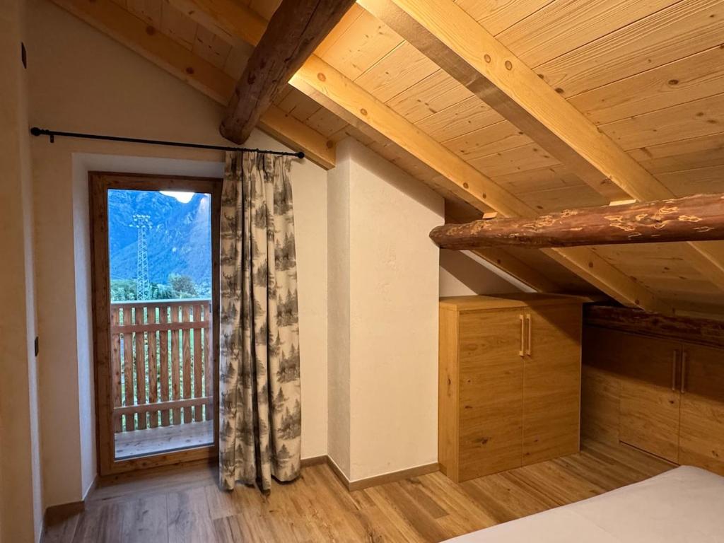 a room with a window and a wooden ceiling at Caluma El Paradis in Comune Rivamonte Agordino