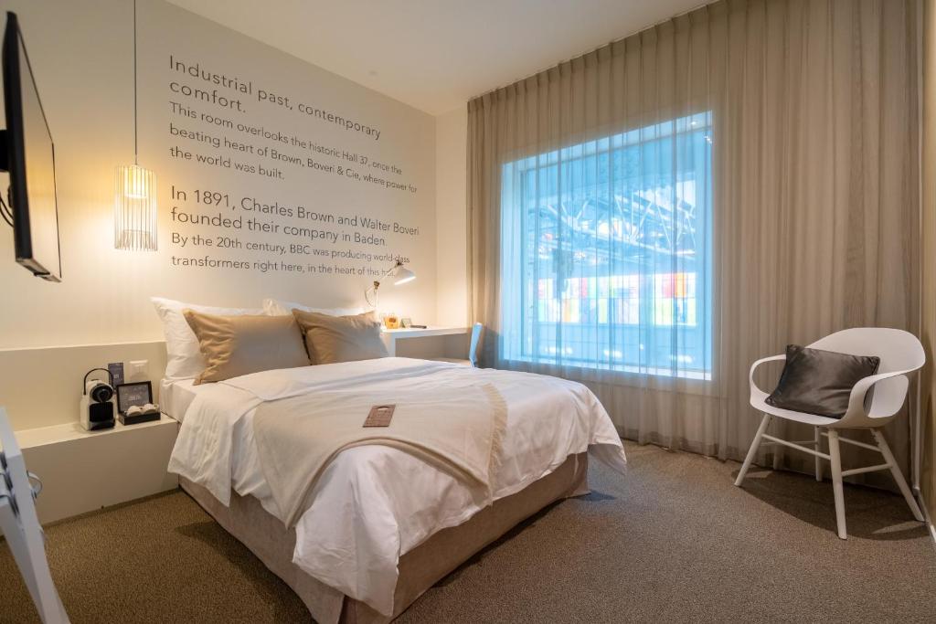 a bedroom with a bed and a window and a chair at Trafo Hotel Baden in Baden