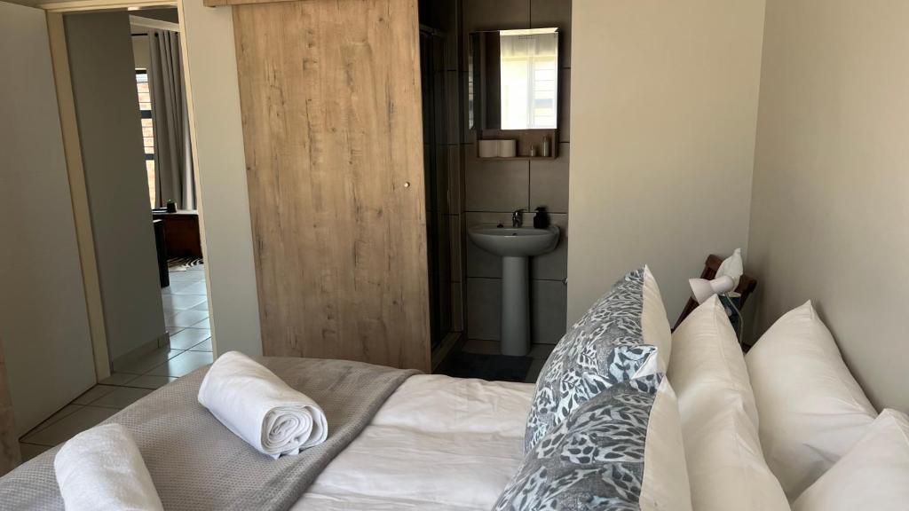 a bedroom with a white bed and a sink at MiCasa 62 in Potchefstroom