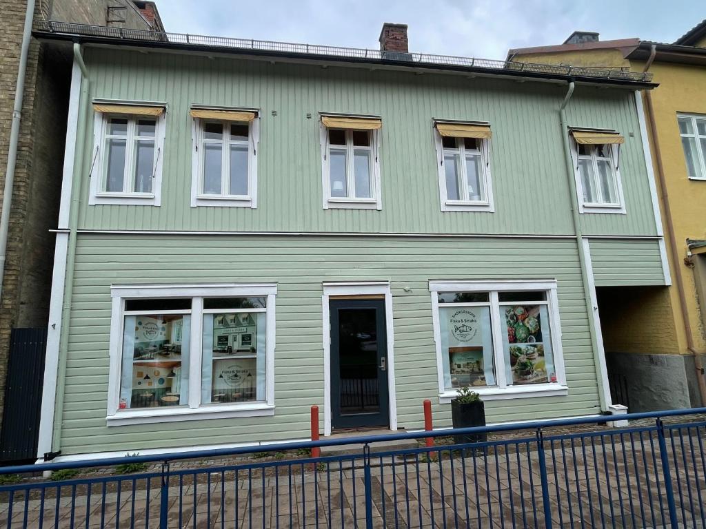 a green house with white windows on a street at Entire 4 rooms Cozy apartment in central Älmhult in Älmhult