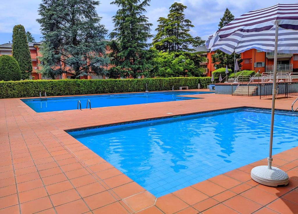 a swimming pool with an umbrella next to a building at Cappuccini Friends in Peschiera del Garda