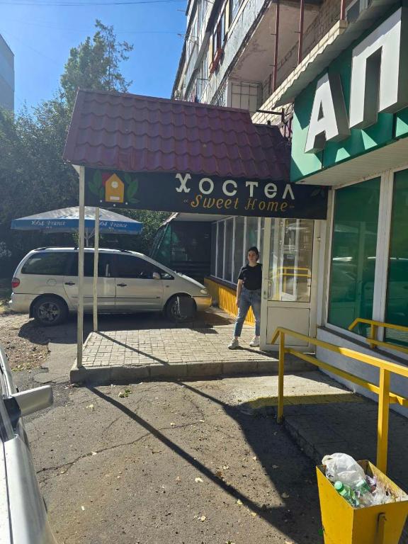 a man walking into a store with a car parked outside at Хостел Sweet Home in Mykolaiv