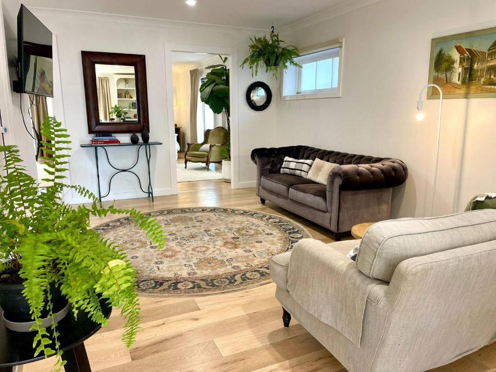 Una sala de estar con dos sofás y una alfombra. en Cosy Guesthouse in Moss Vale, en Moss Vale