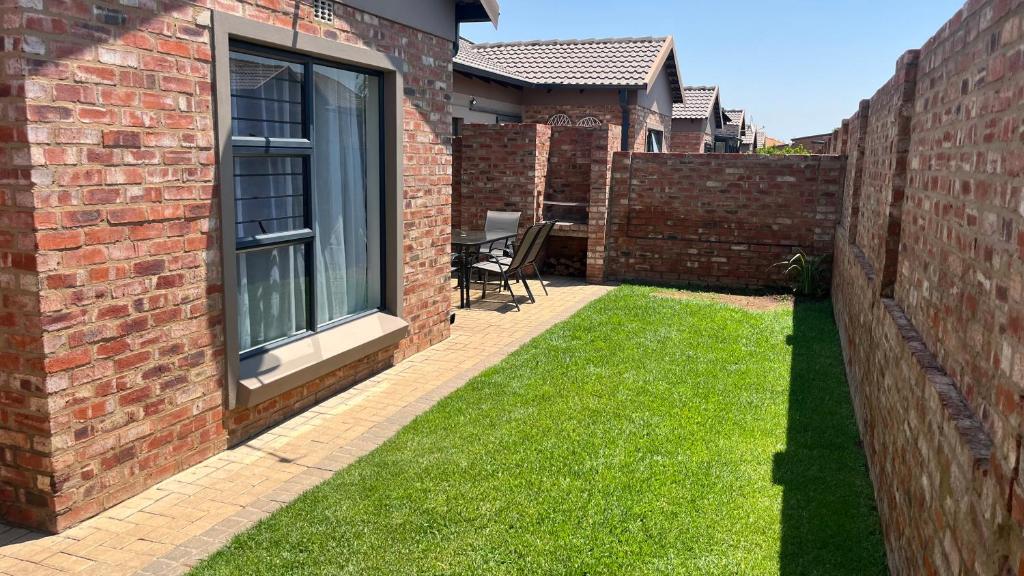 un jardín con una pared de ladrillo y césped en MiCasa 62, en Potchefstroom