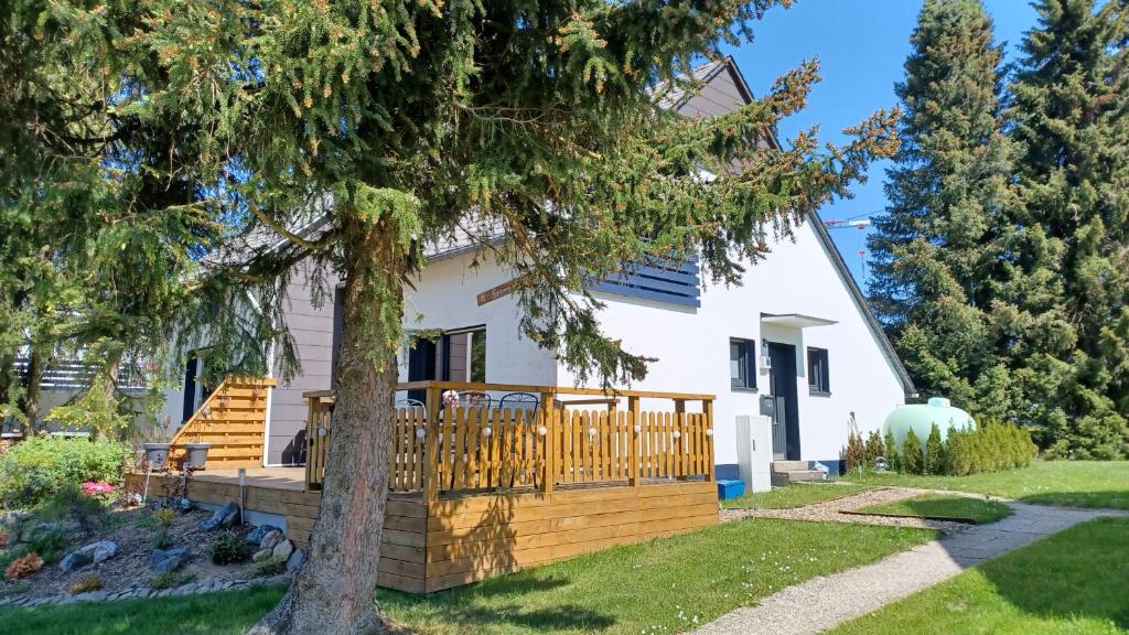 a house with a deck and a tree at Fennies Hütte in Medebach