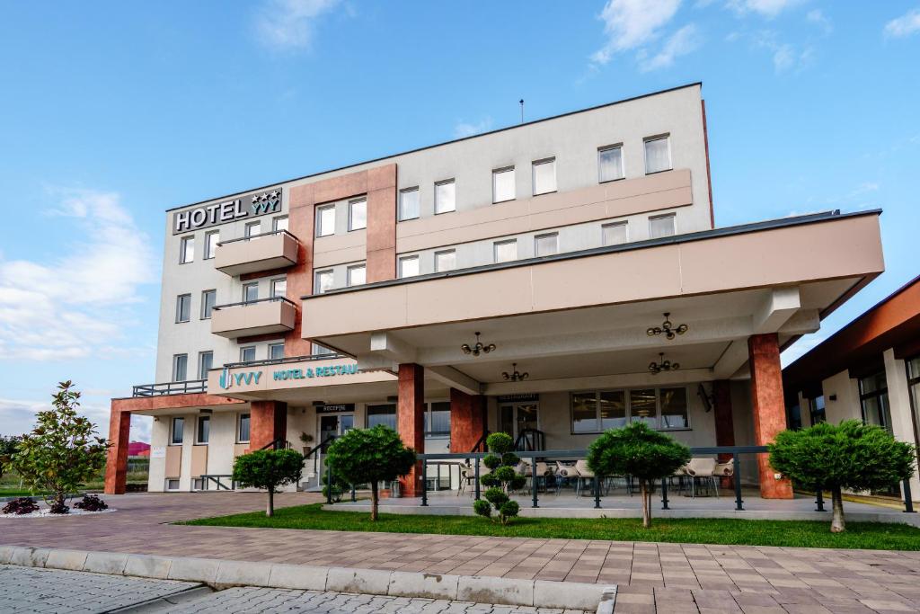 un edificio de hotel con árboles delante de él en Hotel YVY, en Sebeş