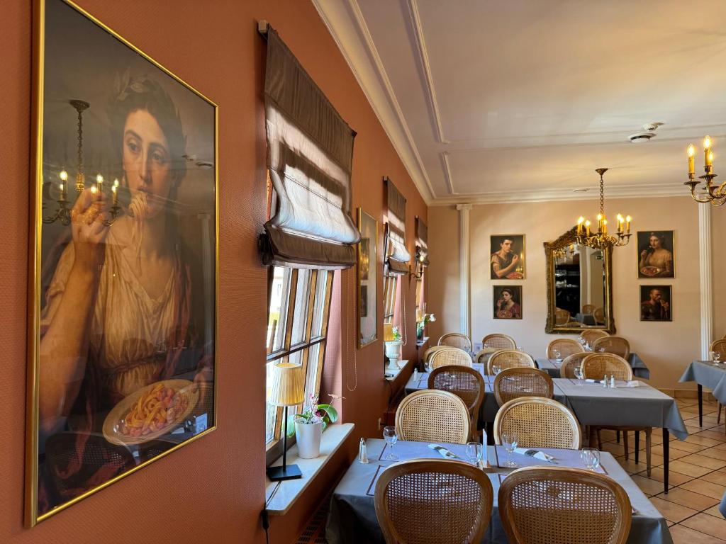 ein Restaurant mit Tischen und Stühlen und einem großen Gemälde an der Wand in der Unterkunft Hotel Casa Borghese in Senningerberg
