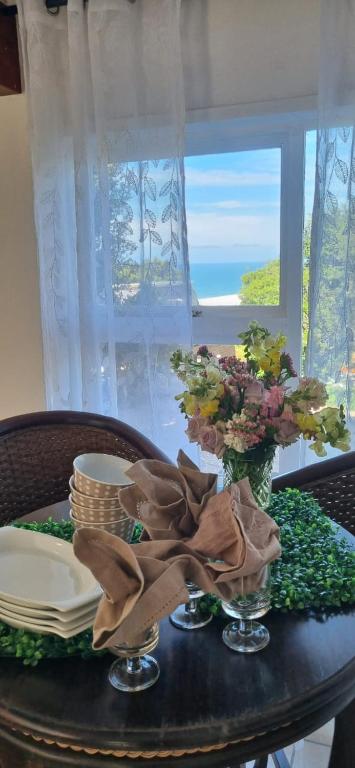 a table with plates and flowers on a table with a window at Dinky's Place in Herolds Bay