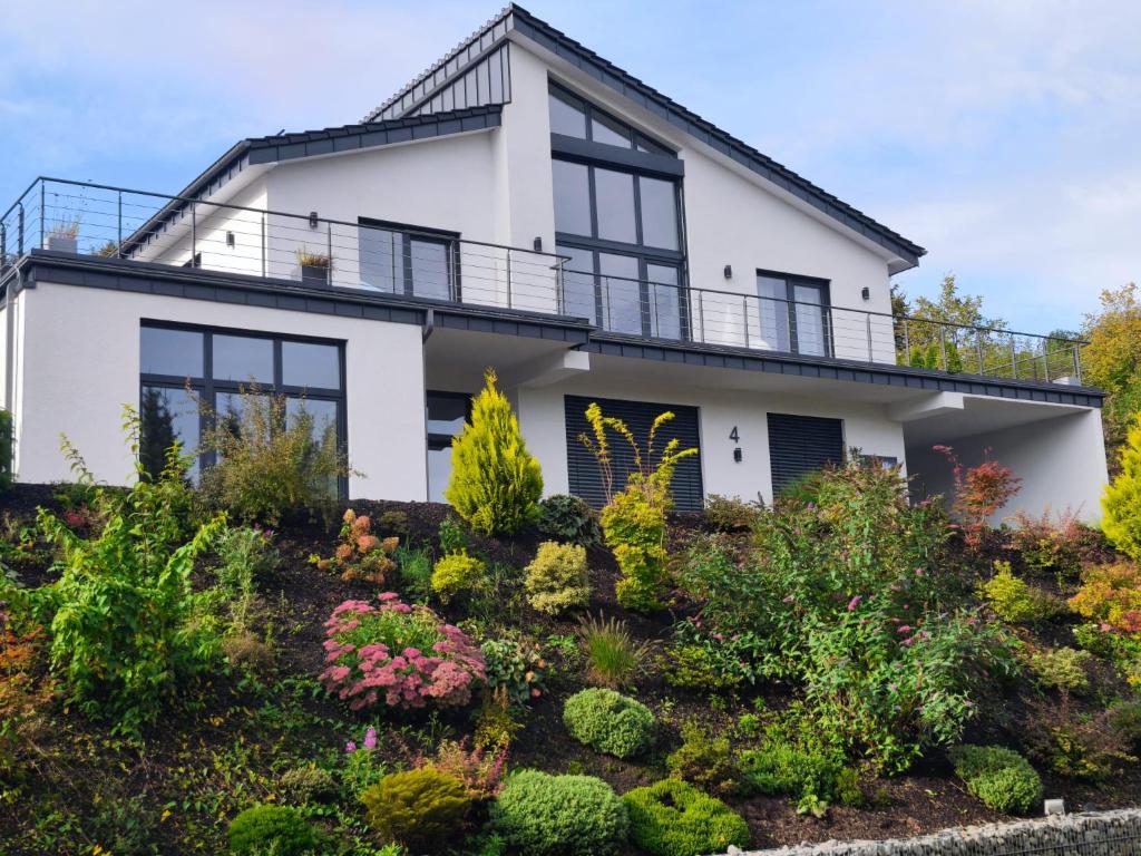 een wit huis met zwarte ramen en planten bij Modernes Apartment in ruhiger Lage inklusive Fitnessgeräte für Ihr Workout zu Hause in Drolshagen