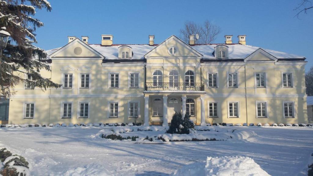 a large white house with snow on the ground at Hotel Sobienie Królewskie in Sobienie Szlacheckie