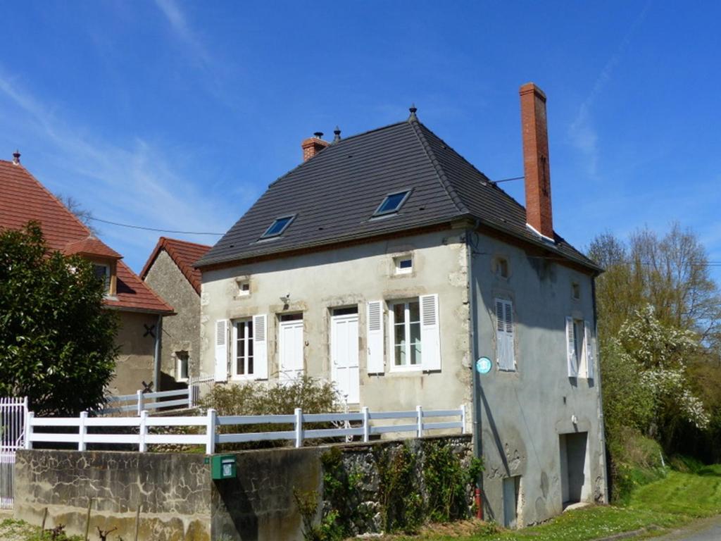 an old white house with a black roof at Gîte de Charme Rénové avec SPA, Jardin et Activités Familiales à Bransat - FR-1-489-295 in Bransat