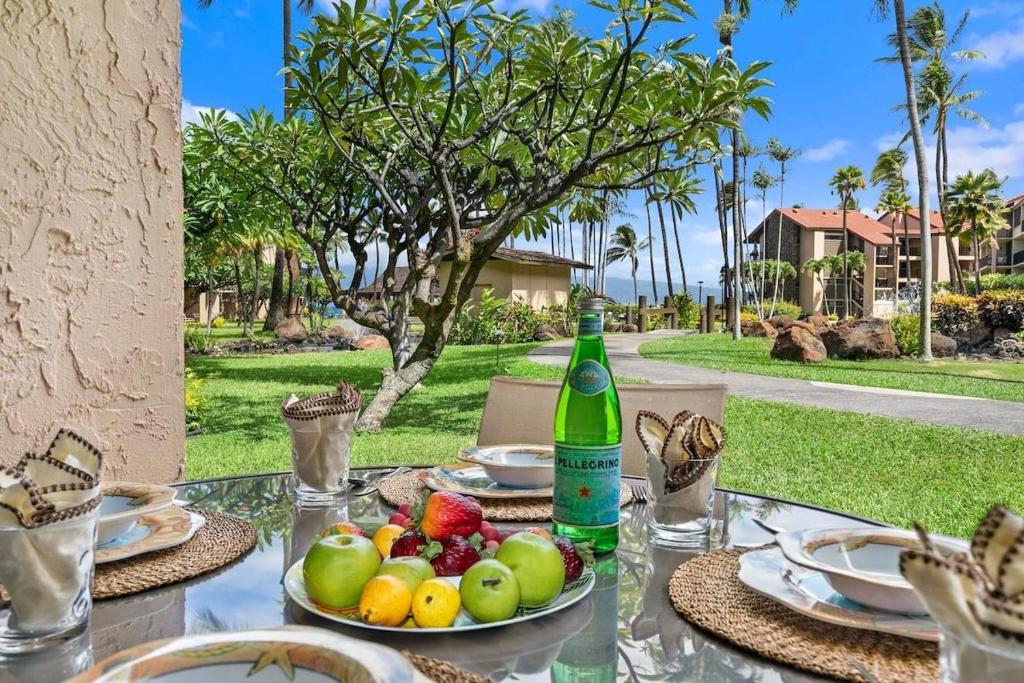 a table with a bottle of wine and fruit on it at Papakea D108 · PK D108 Spacious Condo at BeachFront Resort in Kahana
