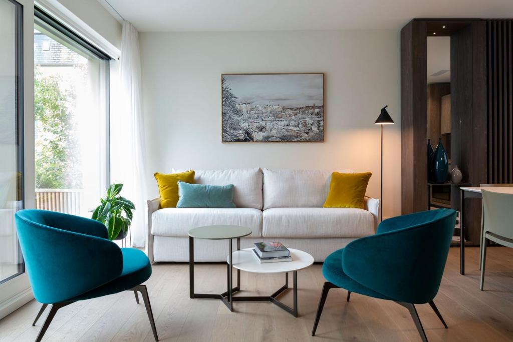 a living room with a white couch and blue chairs at The Central City - Luxury Serviced Residence in Luxembourg
