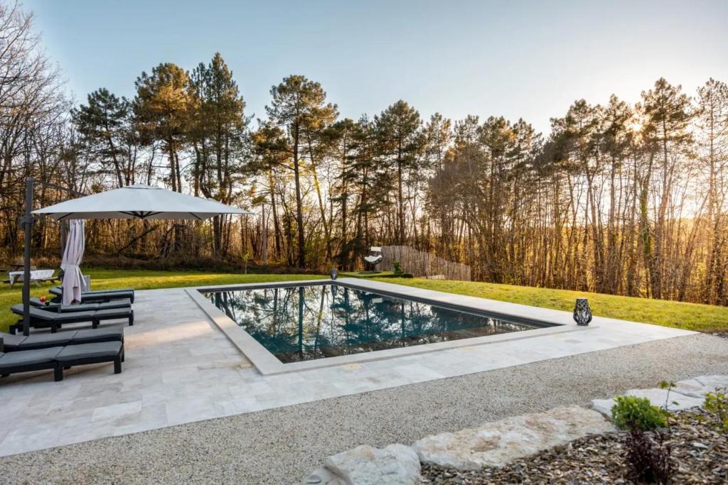 a swimming pool with an umbrella and two chairs at Domaine Le Rucher des Combes in Fleurac