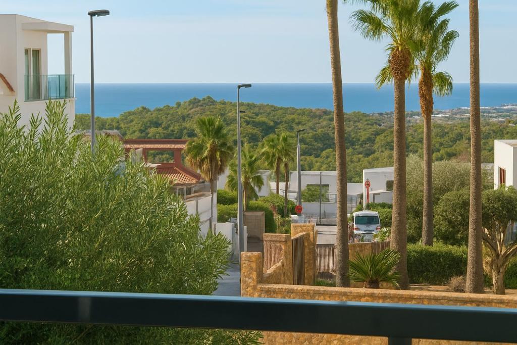 Elle offre une vue sur une rue bordée de palmiers et l'océan. dans l'établissement Villa De Lujo Benidorm Vista al mar, à Finestrat
