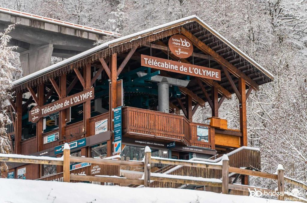 a building in the snow with signs on it at Alba Lodge, 2 min de la télécabine, vue montagnes in Brides-les-Bains