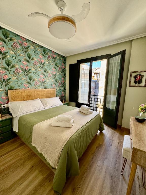 Un dormitorio con una cama grande con sábanas verdes y papel tapiz floral. en Bulebule - Acogedor apartamento en pleno centro de Ourense, en Ourense