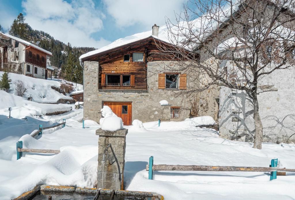 a log cabin in the snow with a snow covered yard at Sunny, rustical 5 room cottage in Valposchiavo in Poschiavo