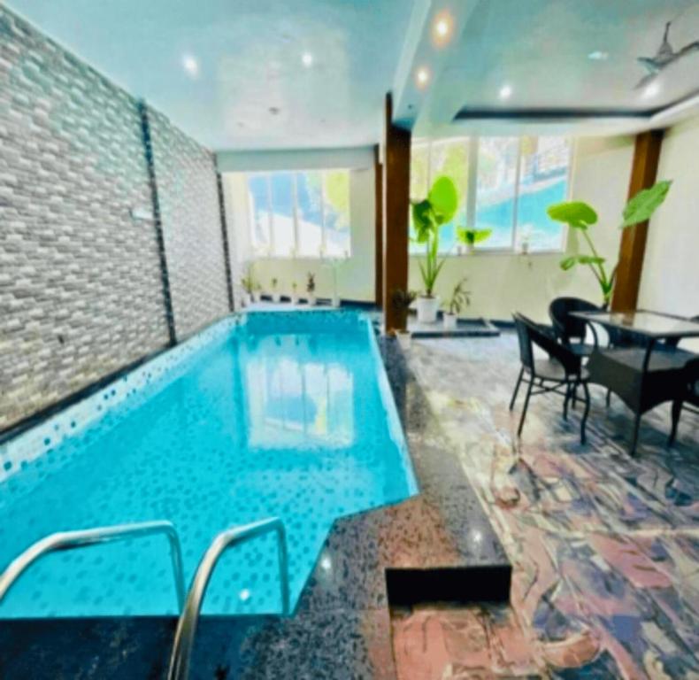 a large swimming pool with a table and chairs in a room at Hotel the shore by Trindra Hospitality in Rishīkesh