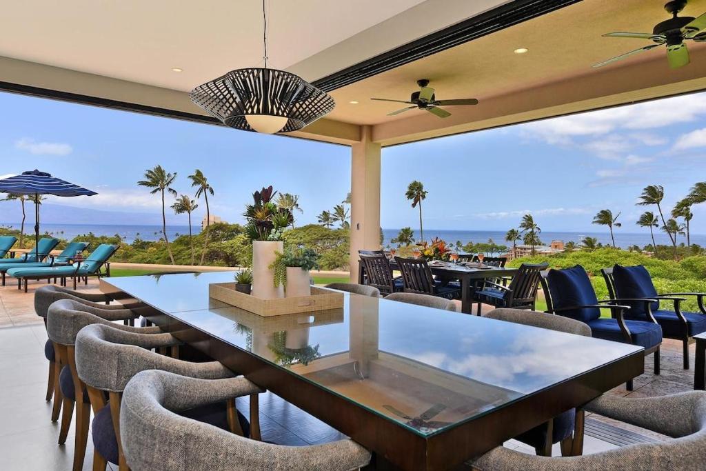カアナパリにあるHale Nui · HALE NUI Luxury Retreat 5BD w Private Pool Hot Tubのテーブルと椅子があり、海の景色が見えるパティオ