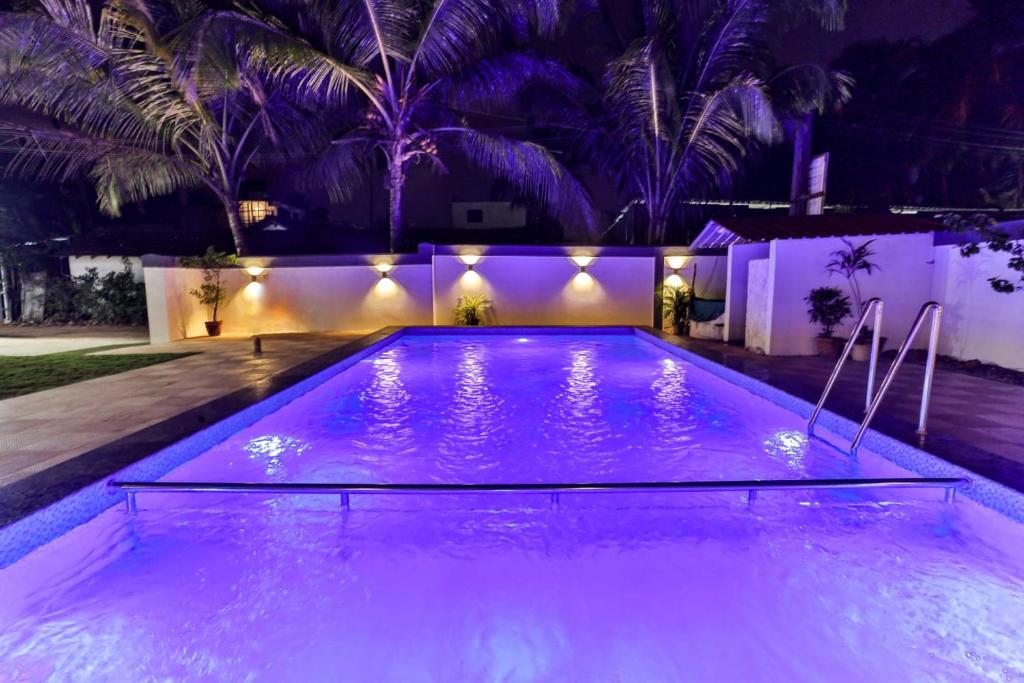 a swimming pool lit up at night with purple lights at Antonio's hotel in Calangute