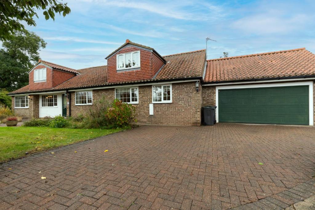 a brick house with a green garage at Ferndene House in Darlington