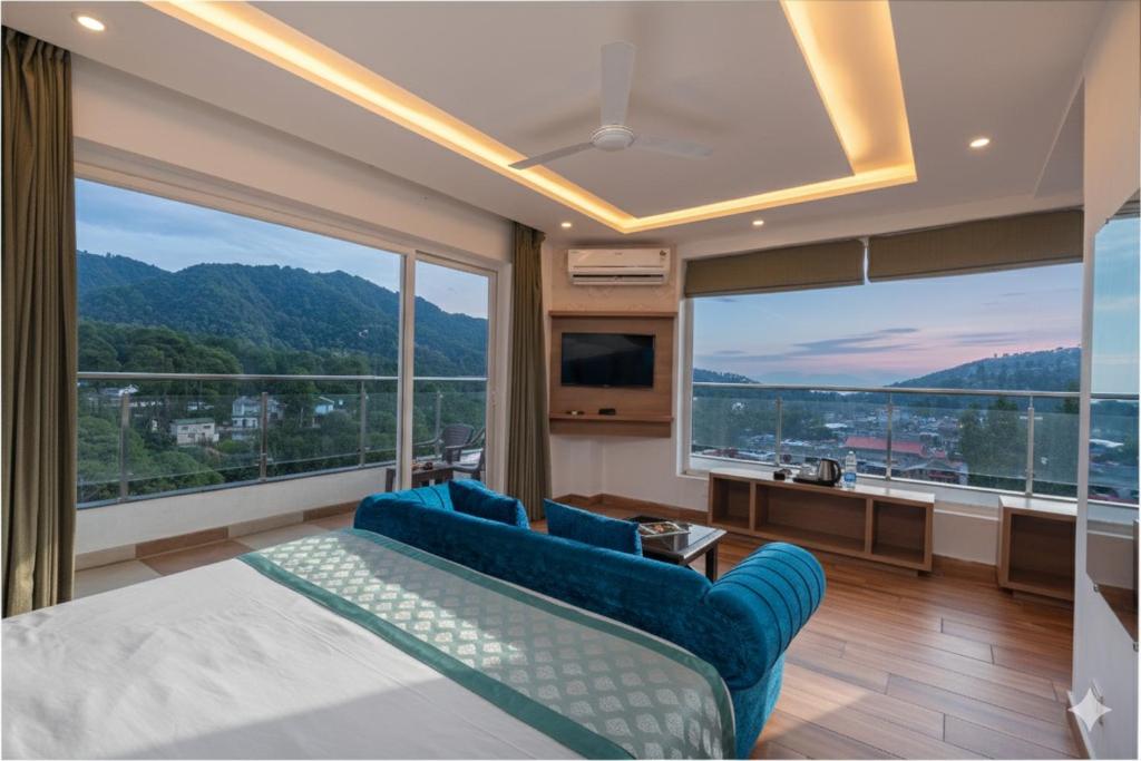 a bedroom with a blue couch and a large window at Hotel Moonglade By Royal Stays Dalhousie in Dalhousie