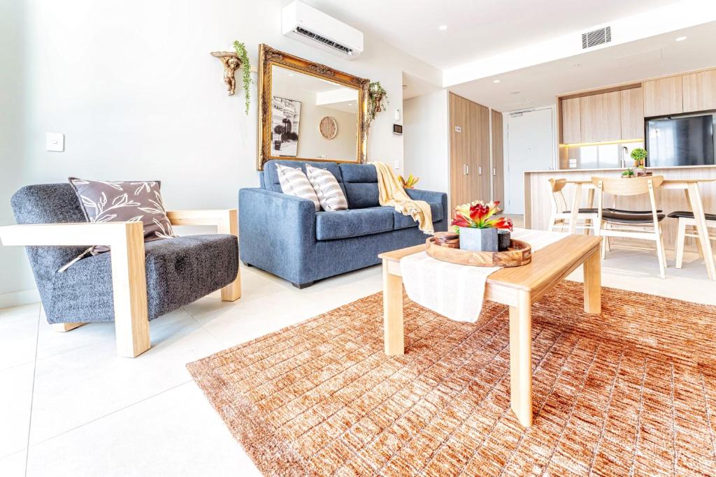 a living room with a blue couch and a table at 412 on CODA Oasis with Mountain View in Coffs Harbour