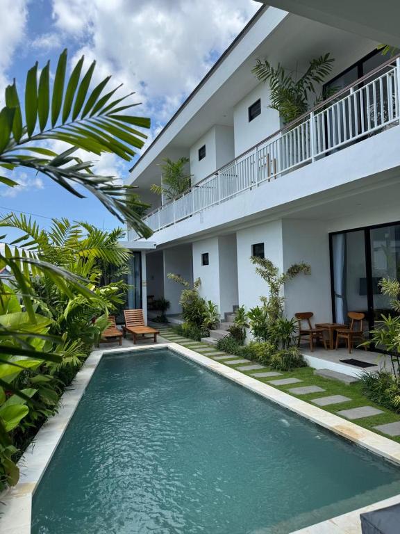a villa with a swimming pool in front of a house at Famiglie Guest House in Canggu