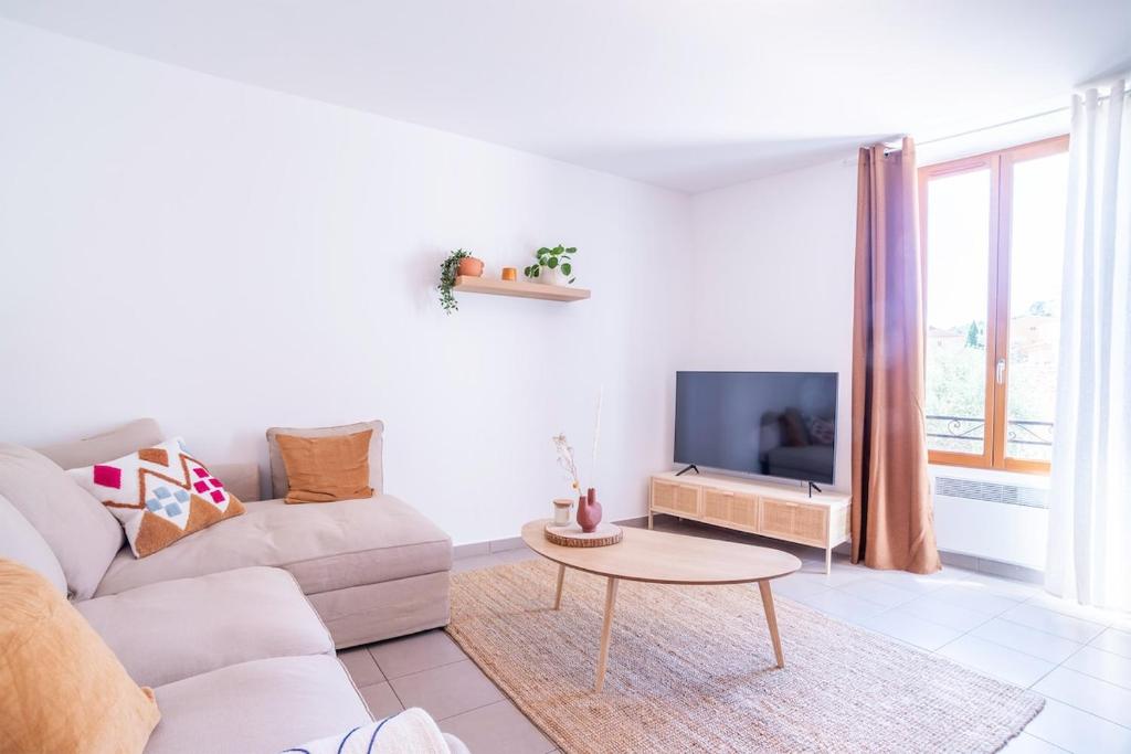 Una sala de estar blanca con un sofá y un televisor. en Bright and confortable apartment in downtown BLM, en Bormes-les-Mimosas