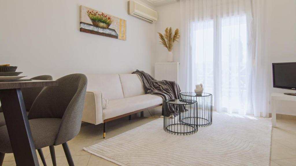 a white living room with a couch and a tv at Perdika Residences in Perdika