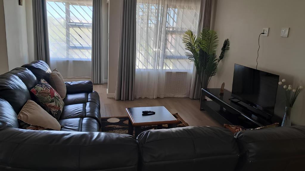 a living room with a leather couch and a table at Terrys place in Malmesbury