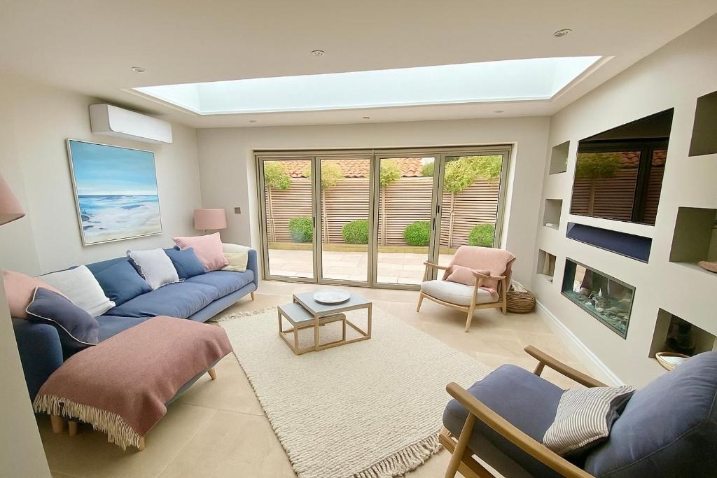 a living room with blue couches and a window at Boutique Burnham Market Cottage in Burnham Market