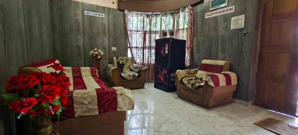 a bedroom with a bed and two chairs and flowers at Sheshu Homestay in Māvalli