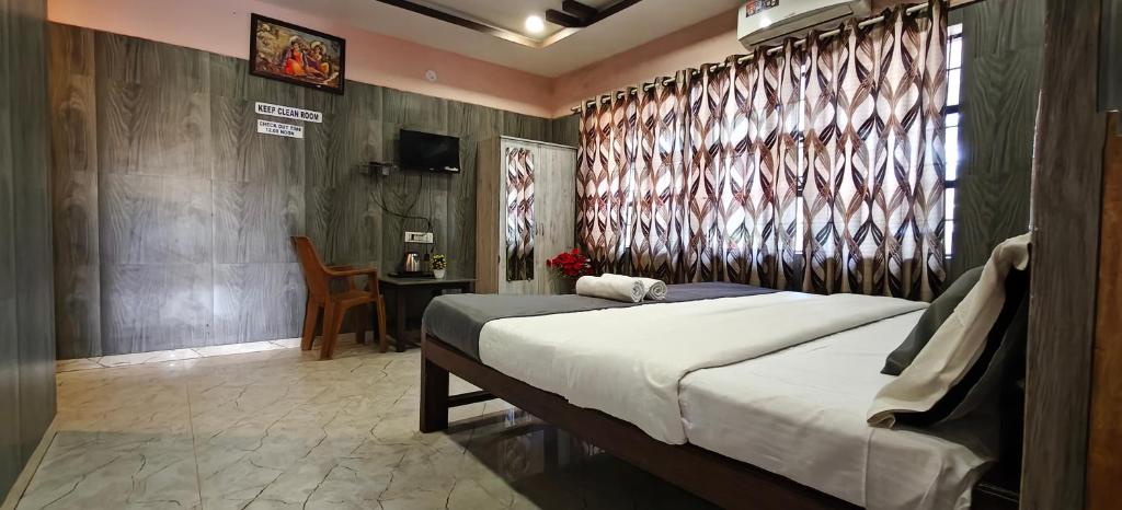 een slaapkamer met een bed en een tafel met een stoel bij Sheshu Homestay in Māvalli