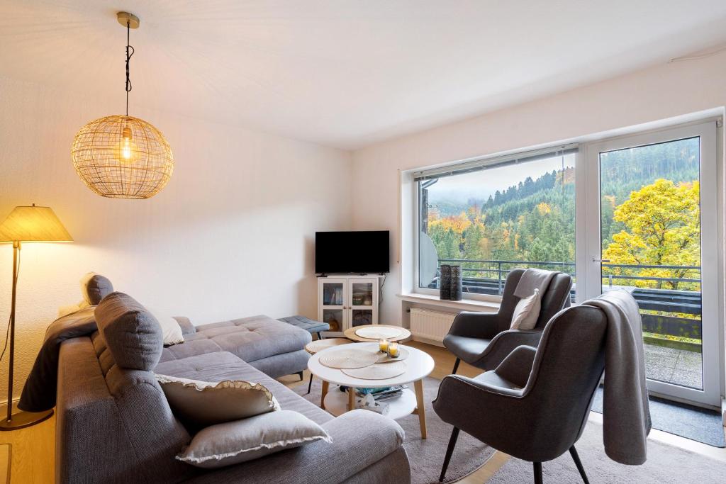 a living room with a couch and chairs and a large window at Ferienwohnung Wald-Ausblick in Willingen