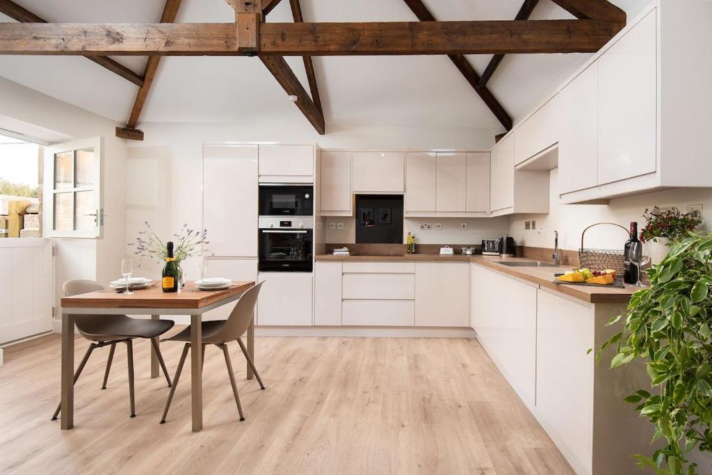 a kitchen with white cabinets and a wooden table at The Smithy at West Lyham in Chatton