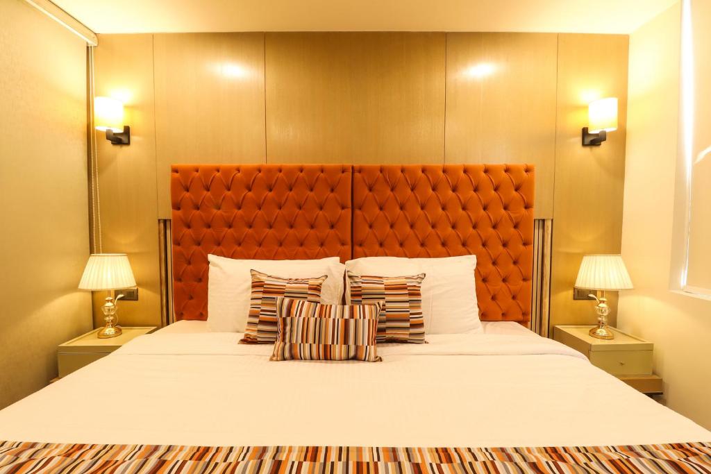 a bedroom with a large white bed with two lamps at AR Suites Sohna Road in Gurgaon