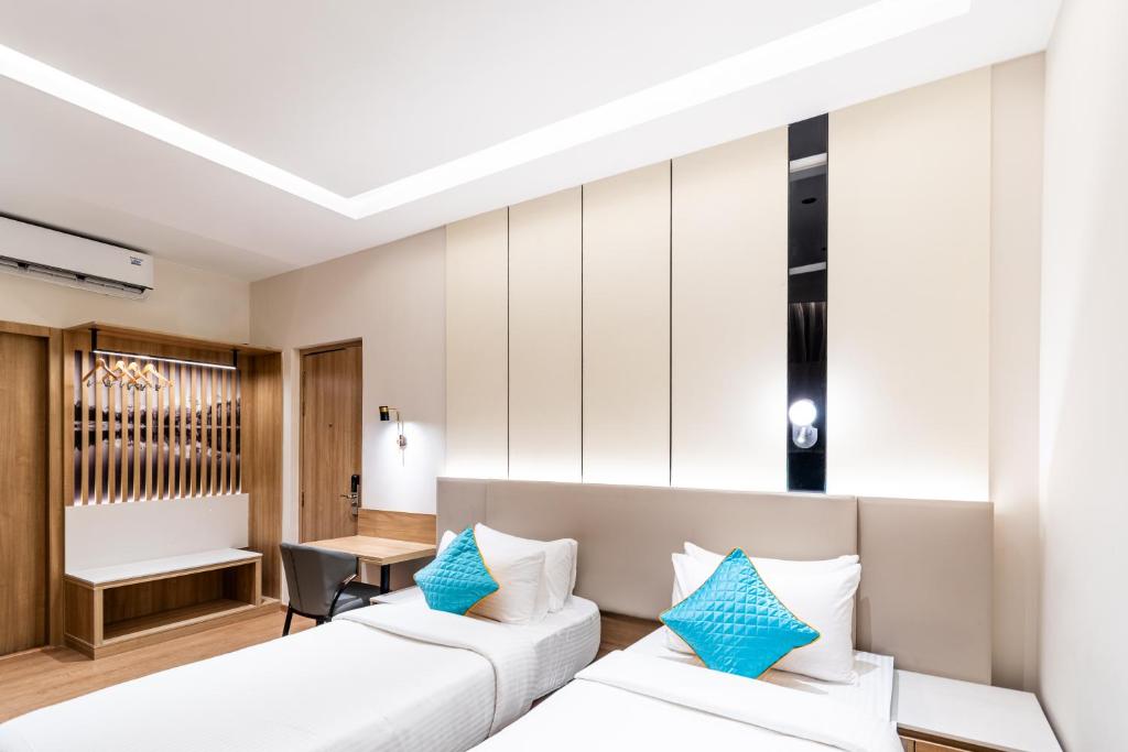 two beds in a hotel room with blue pillows at Hotel Lenexa by Bestinn Leisure in Bengaluru