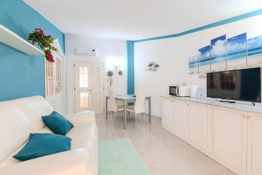un salon avec un canapé blanc et une télévision dans l'établissement Grazia Deledda - Oasis of Relaxation -, à Olbia