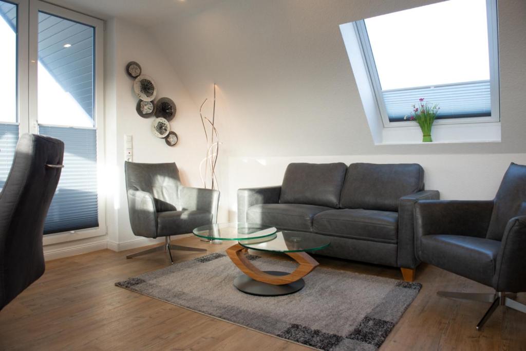 un soggiorno con divano, 2 sedie e tavolo di Deichstübchen oben a Norddeich