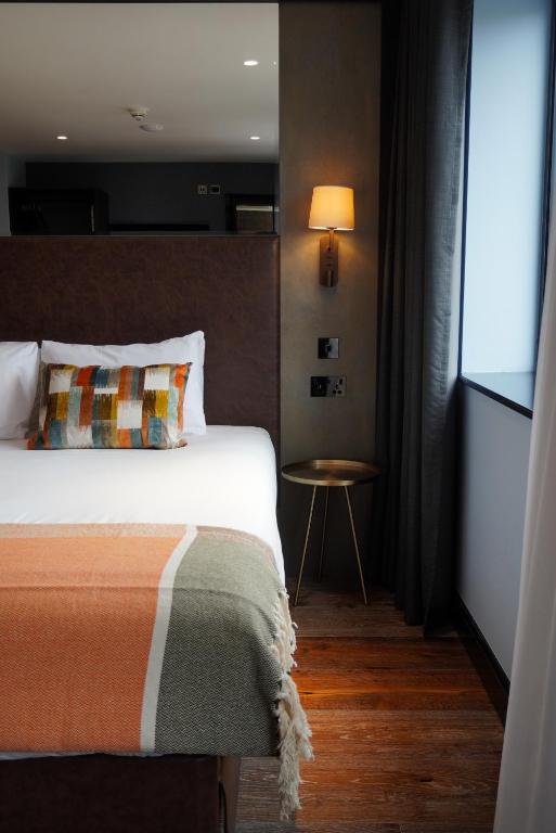 a bedroom with a bed and a table with a lamp at The Camden Town Hotel in London