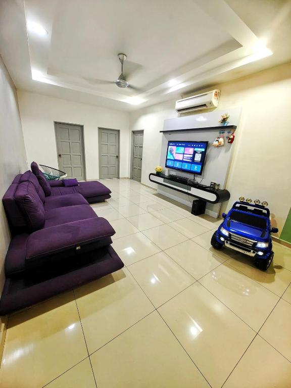 un salon avec un canapé violet et une télévision dans l'établissement Fun Fun Stay Tangkak by GX Homestay, à Tangkak