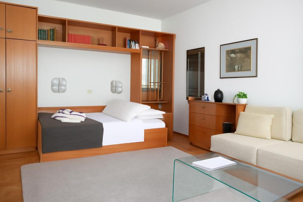 a bedroom with a bed and a couch and a glass table at ML Apartman in Belgrade