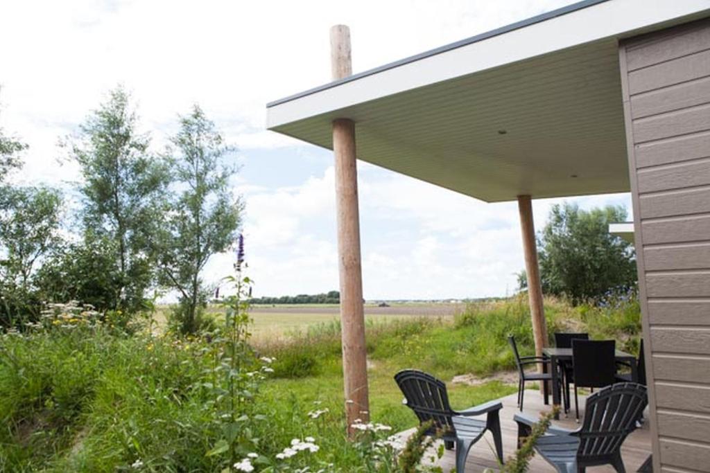 a patio with chairs and a table under a roof at Strand49 Glamping Sint Maartenszee in Sint Maartensvlotbrug