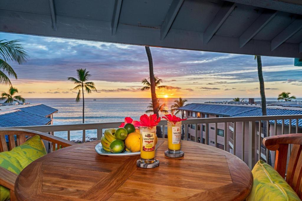 a wooden table with a plate of fruit on a balcony at Kona Reef F22 condo in Kailua-Kona