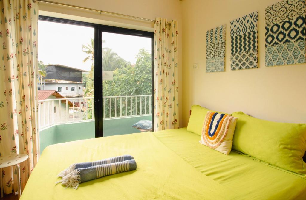 a bedroom with a yellow bed and a window at Odd Table in Mandrem